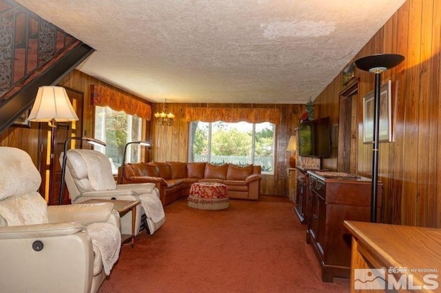 living room featuring carpet, wood walls, a textured ceiling, and a chandelier