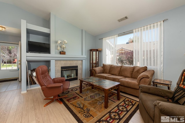 living room with a fireplace, hardwood / wood-style floors, lofted ceiling, and a wealth of natural light