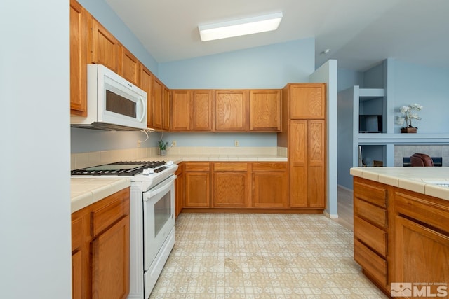 kitchen with white appliances, vaulted ceiling, and tile countertops