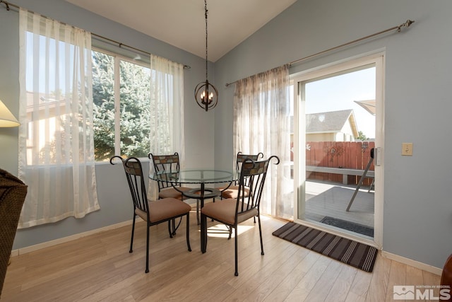 dining space featuring vaulted ceiling, a chandelier, and light hardwood / wood-style floors