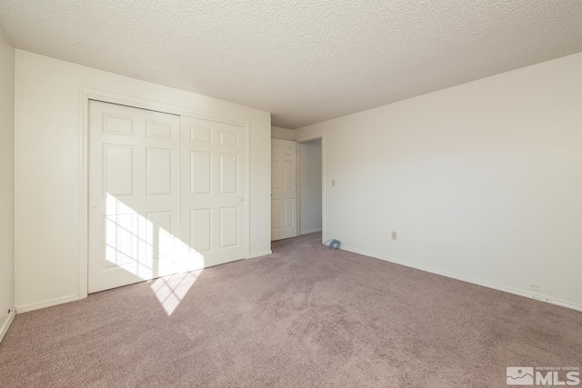 unfurnished bedroom with light carpet, a textured ceiling, and a closet