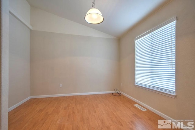 empty room featuring light wood-type flooring, vaulted ceiling, and plenty of natural light