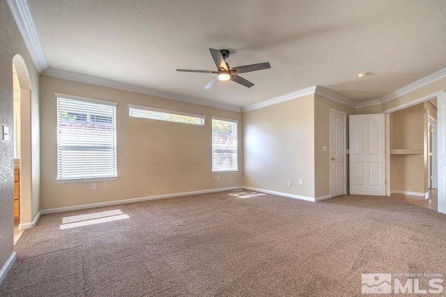 empty room with ceiling fan, crown molding, and carpet