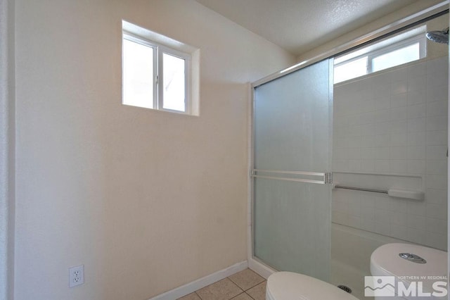 bathroom with tile patterned flooring, a shower with shower door, and toilet