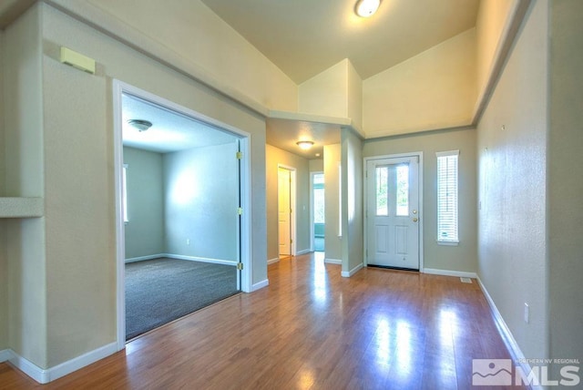 entryway with wood-type flooring and lofted ceiling