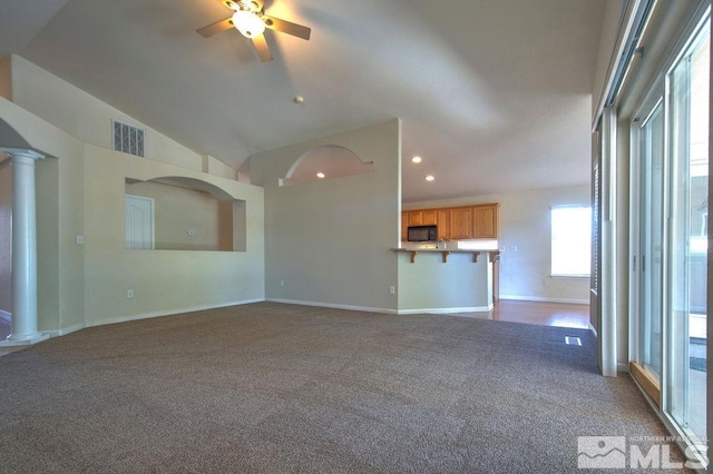 unfurnished living room featuring carpet, lofted ceiling, ceiling fan, and ornate columns