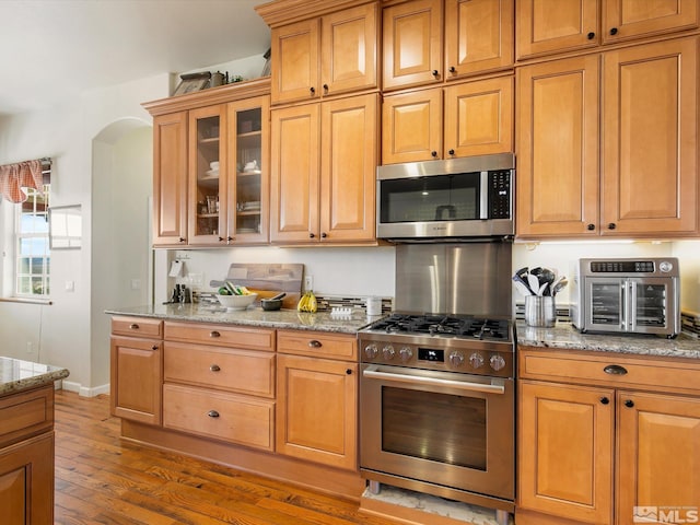 kitchen featuring light stone countertops, appliances with stainless steel finishes, and light hardwood / wood-style flooring