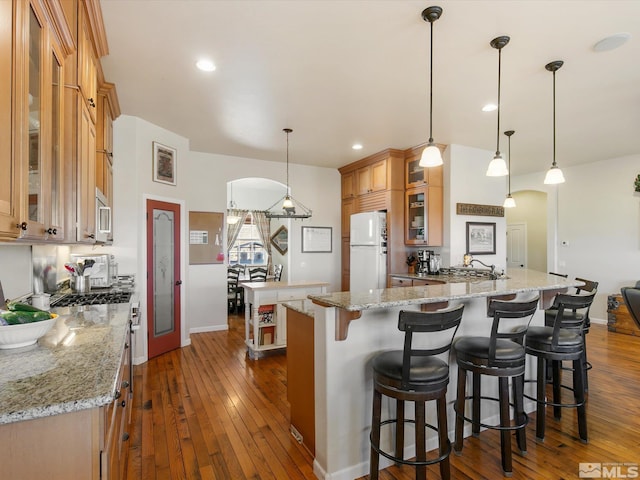 kitchen featuring white appliances, a spacious island, dark hardwood / wood-style floors, and decorative light fixtures