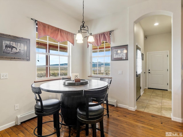 dining room with a notable chandelier, baseboard heating, and hardwood / wood-style floors