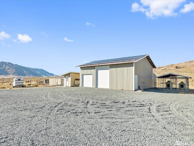 view of outdoor structure with a mountain view, a carport, and a garage