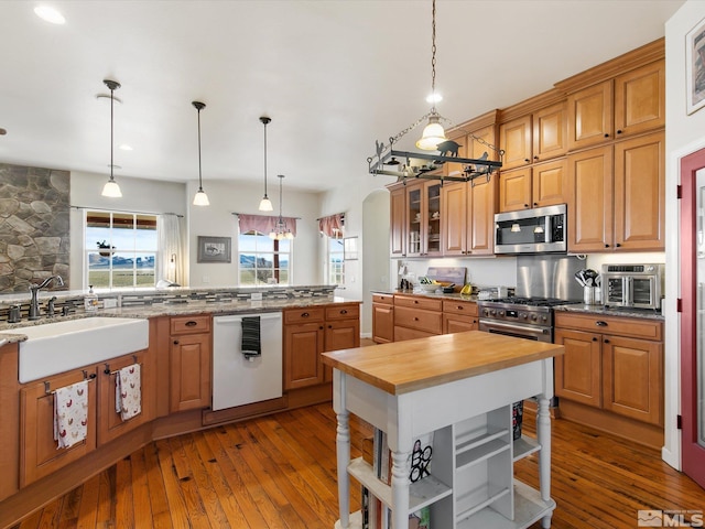 kitchen with light hardwood / wood-style floors, sink, white dishwasher, and decorative light fixtures