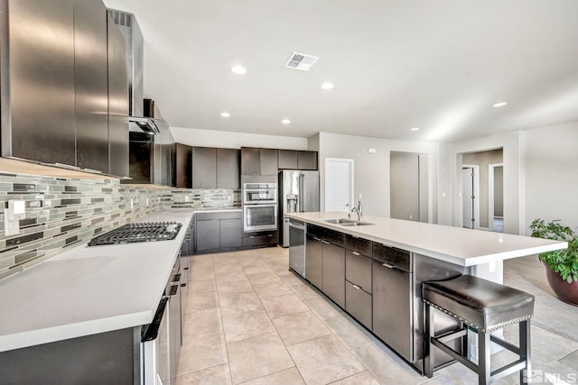 kitchen featuring a kitchen island with sink, a breakfast bar area, sink, and stainless steel appliances