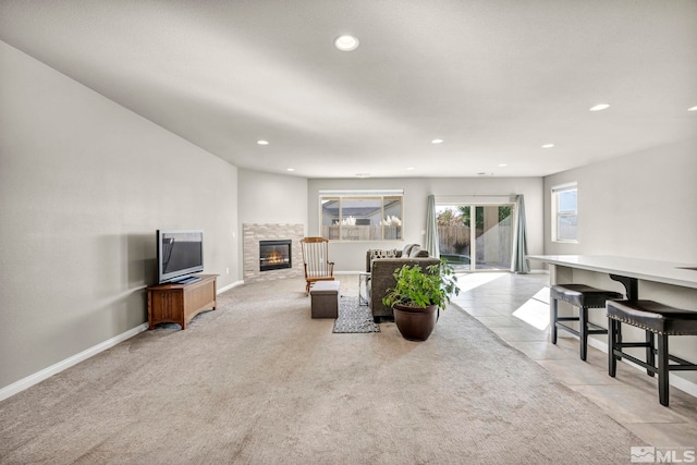 carpeted living room featuring a stone fireplace