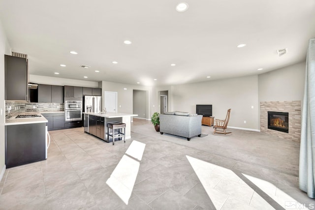 kitchen featuring light tile patterned flooring, tasteful backsplash, a kitchen island, a kitchen breakfast bar, and appliances with stainless steel finishes