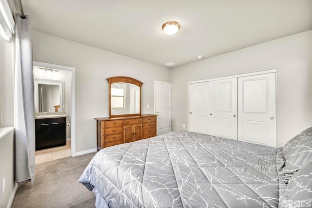 carpeted bedroom with ensuite bath, a closet, and sink