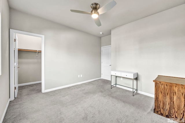 unfurnished bedroom with carpet, a spacious closet, ceiling fan, and a closet