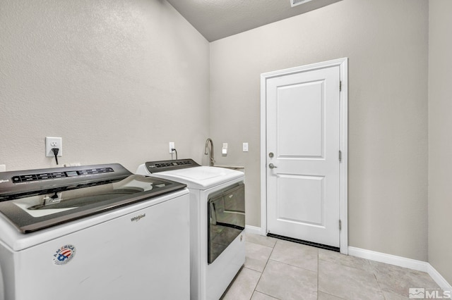 laundry room with a textured ceiling, light tile patterned flooring, and washer and clothes dryer