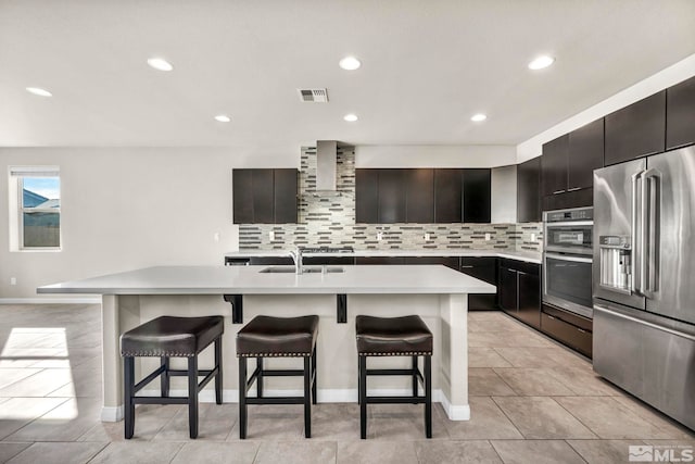 kitchen with a kitchen island with sink, appliances with stainless steel finishes, sink, and a kitchen bar