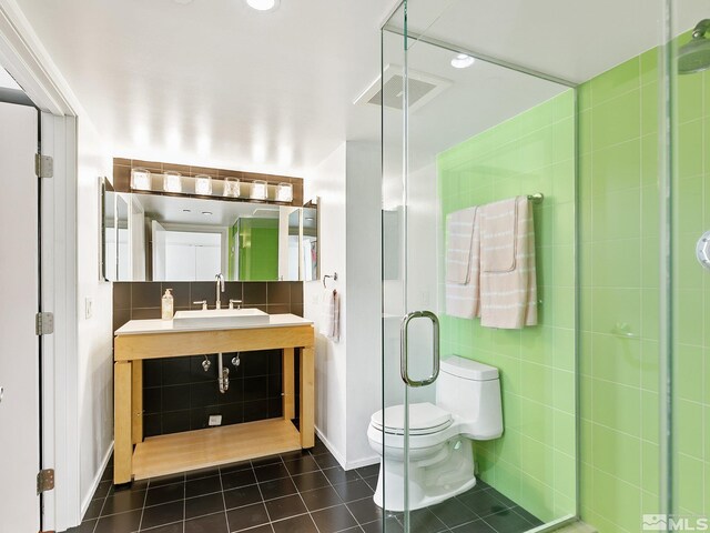 bathroom with tile walls, sink, a shower with door, tile patterned floors, and toilet