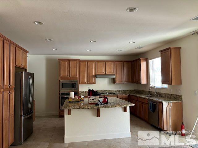 kitchen with sink, a center island, stainless steel appliances, a breakfast bar, and dark stone counters