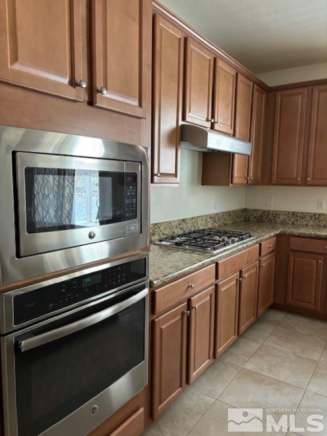 kitchen featuring light stone countertops, light tile patterned flooring, and appliances with stainless steel finishes