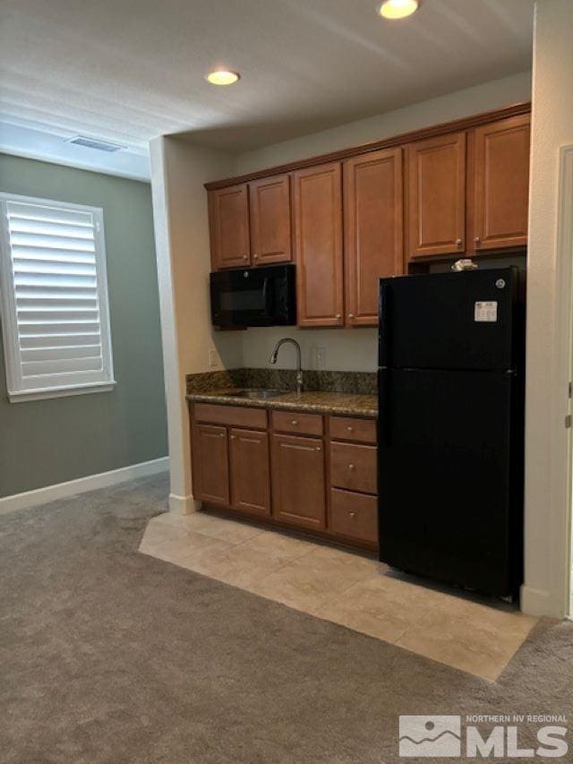 kitchen featuring light colored carpet, dark stone counters, sink, and black appliances