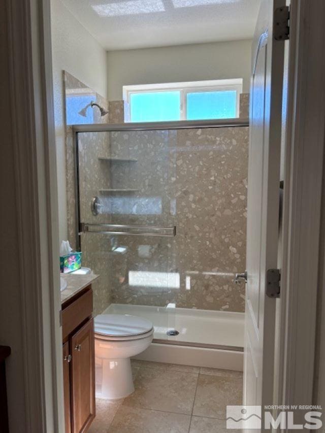 bathroom with a healthy amount of sunlight, a shower with door, toilet, and vanity