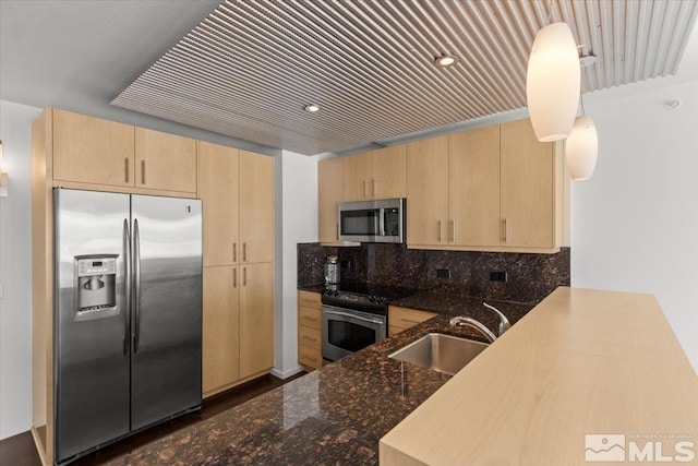 kitchen with stainless steel appliances, kitchen peninsula, light brown cabinetry, and sink