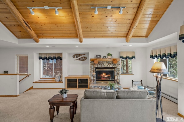 carpeted living room featuring vaulted ceiling with beams, a stone fireplace, baseboard heating, and rail lighting