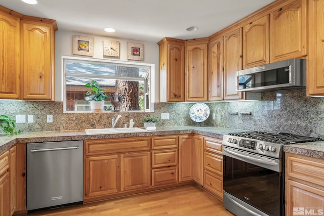 kitchen featuring light hardwood / wood-style flooring, stainless steel appliances, backsplash, and sink