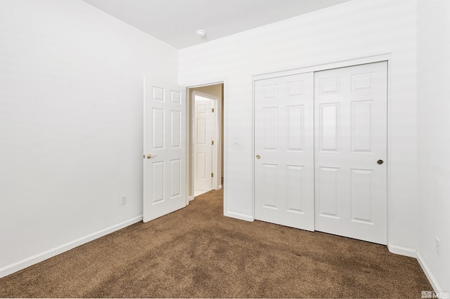 unfurnished bedroom with dark colored carpet and a closet