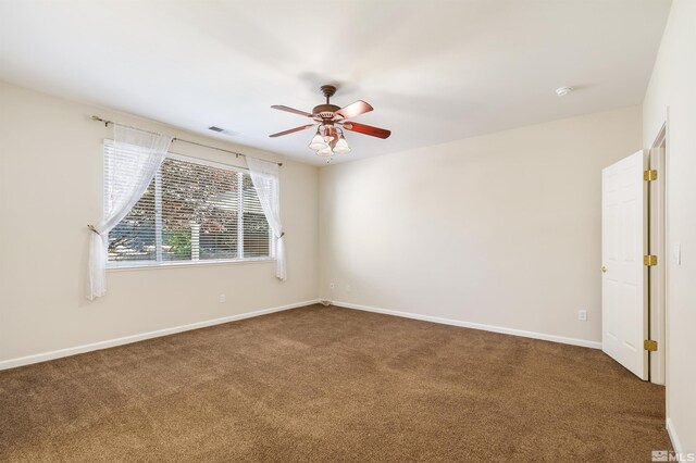 empty room with dark colored carpet and ceiling fan