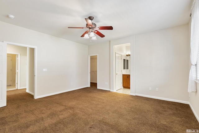 unfurnished bedroom with a walk in closet, light colored carpet, ceiling fan, connected bathroom, and a closet