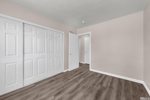 unfurnished bedroom with a closet and dark hardwood / wood-style floors