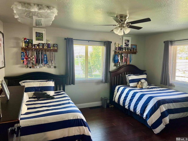 bedroom featuring ceiling fan, multiple windows, dark wood-type flooring, and a textured ceiling