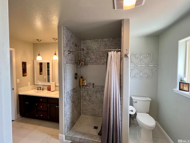 bathroom featuring toilet, vanity, a textured ceiling, tiled shower, and baseboards