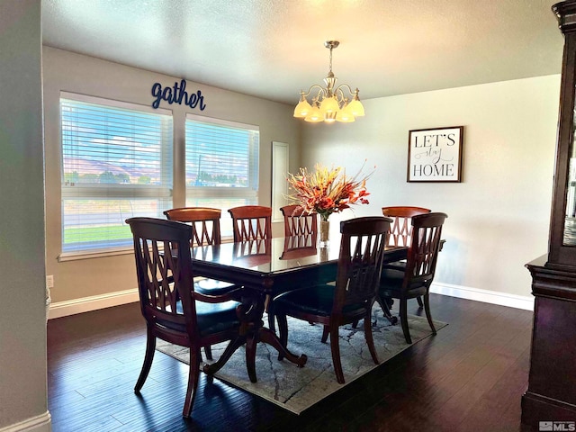 dining area featuring a textured ceiling, an inviting chandelier, dark wood finished floors, and baseboards