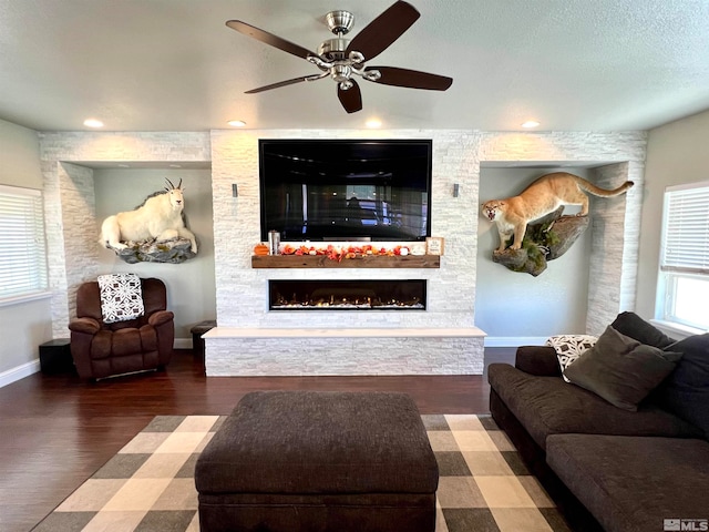 living room with a fireplace, ceiling fan, and dark wood-type flooring