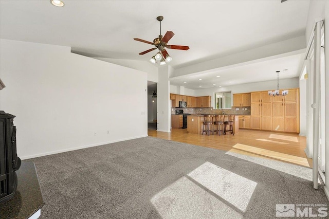 living room featuring ceiling fan with notable chandelier, light hardwood / wood-style floors, and a wood stove