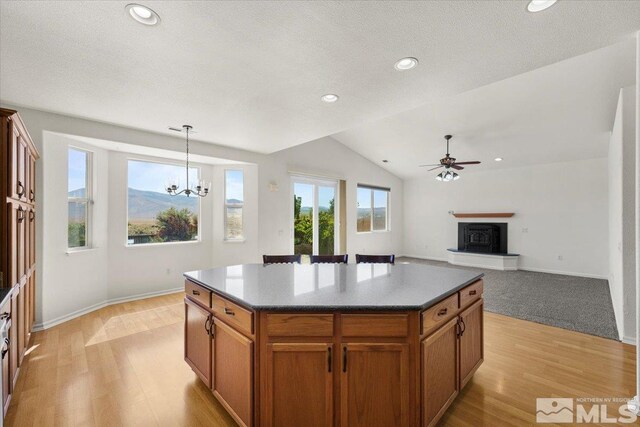 kitchen featuring a center island, ceiling fan with notable chandelier, lofted ceiling, light hardwood / wood-style flooring, and decorative light fixtures