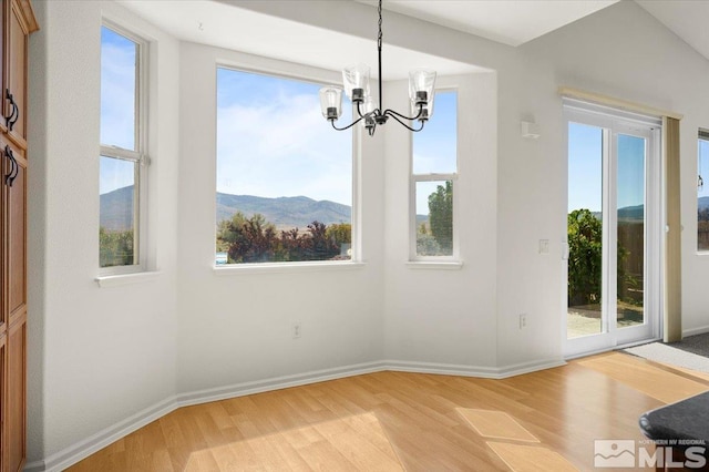 unfurnished dining area featuring light hardwood / wood-style flooring, a mountain view, and plenty of natural light