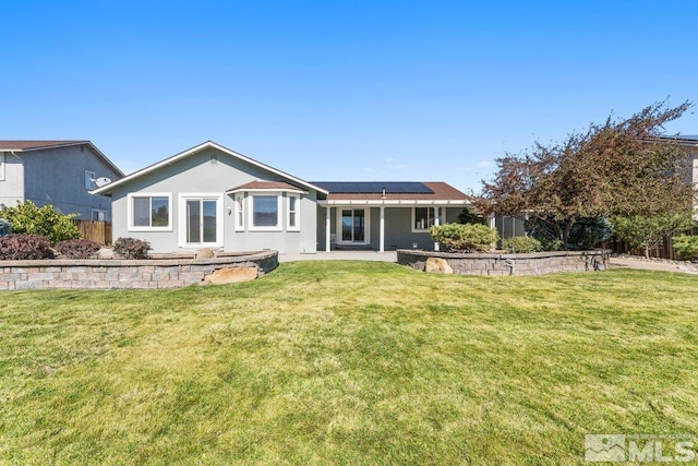 rear view of house with a lawn, solar panels, and a patio