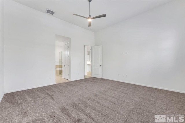 unfurnished bedroom featuring a high ceiling, ceiling fan, light colored carpet, and ensuite bathroom