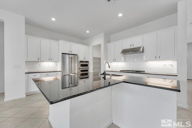 kitchen with light tile patterned flooring, a kitchen island with sink, sink, white cabinets, and stainless steel appliances