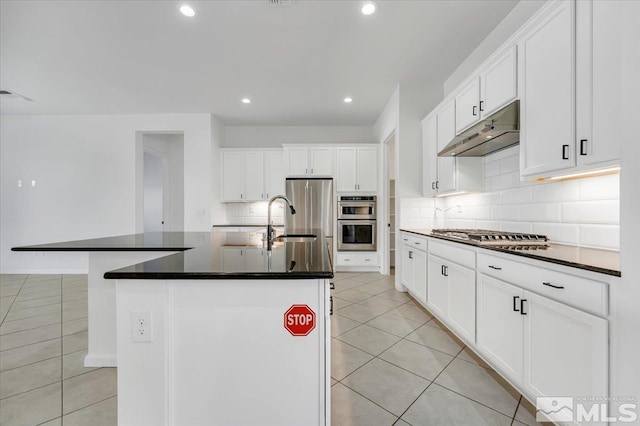 kitchen featuring white cabinetry, tasteful backsplash, light tile patterned floors, stainless steel appliances, and a kitchen island with sink