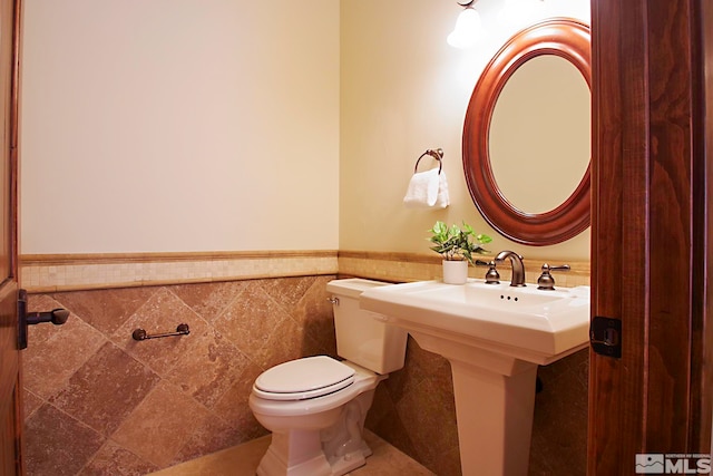 bathroom featuring tile walls and toilet