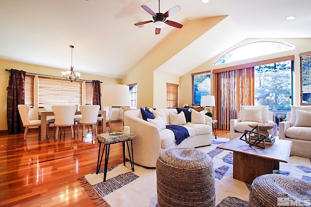 living room with ceiling fan with notable chandelier, light wood-type flooring, and vaulted ceiling