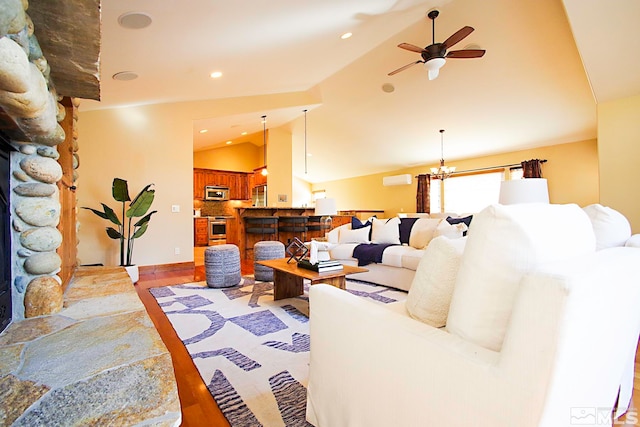 living room with wood-type flooring, ceiling fan with notable chandelier, a fireplace, and lofted ceiling