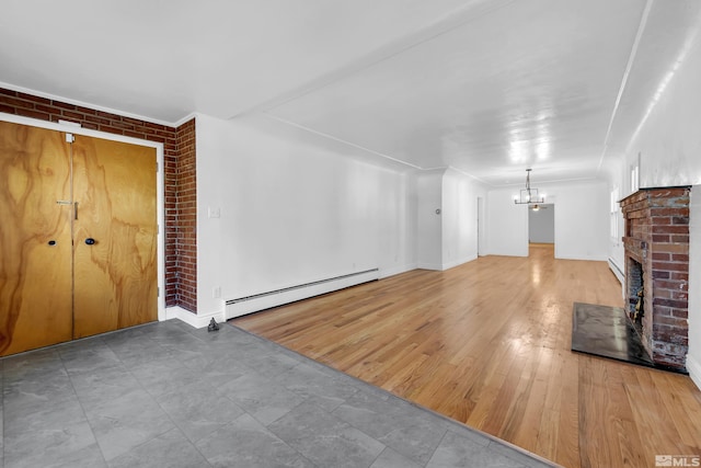 unfurnished living room featuring brick wall, baseboard heating, a fireplace, a notable chandelier, and light wood-type flooring