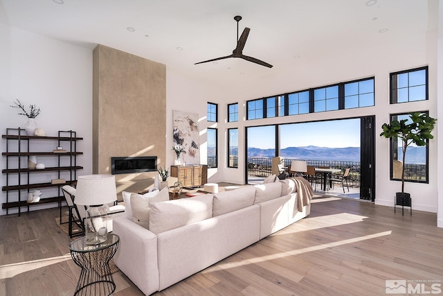 living room with a mountain view, ceiling fan, a fireplace, and hardwood / wood-style floors